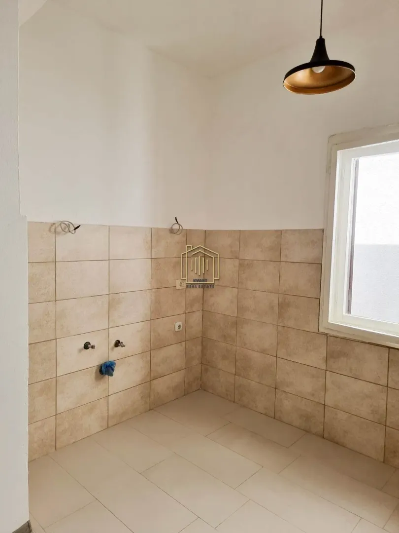 Unfurnished kitchen area with ceramic tiles on the wall and floor.