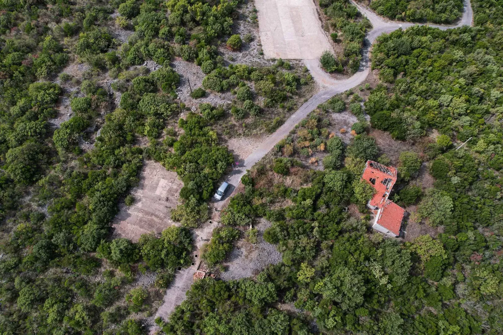 Pogled iz vazduha na zemljište sa ruševinom i pristupnim putem.