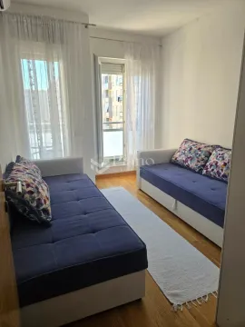 Manja dnevna soba sa dva plava kauča i izlazom na balkon. - image 6