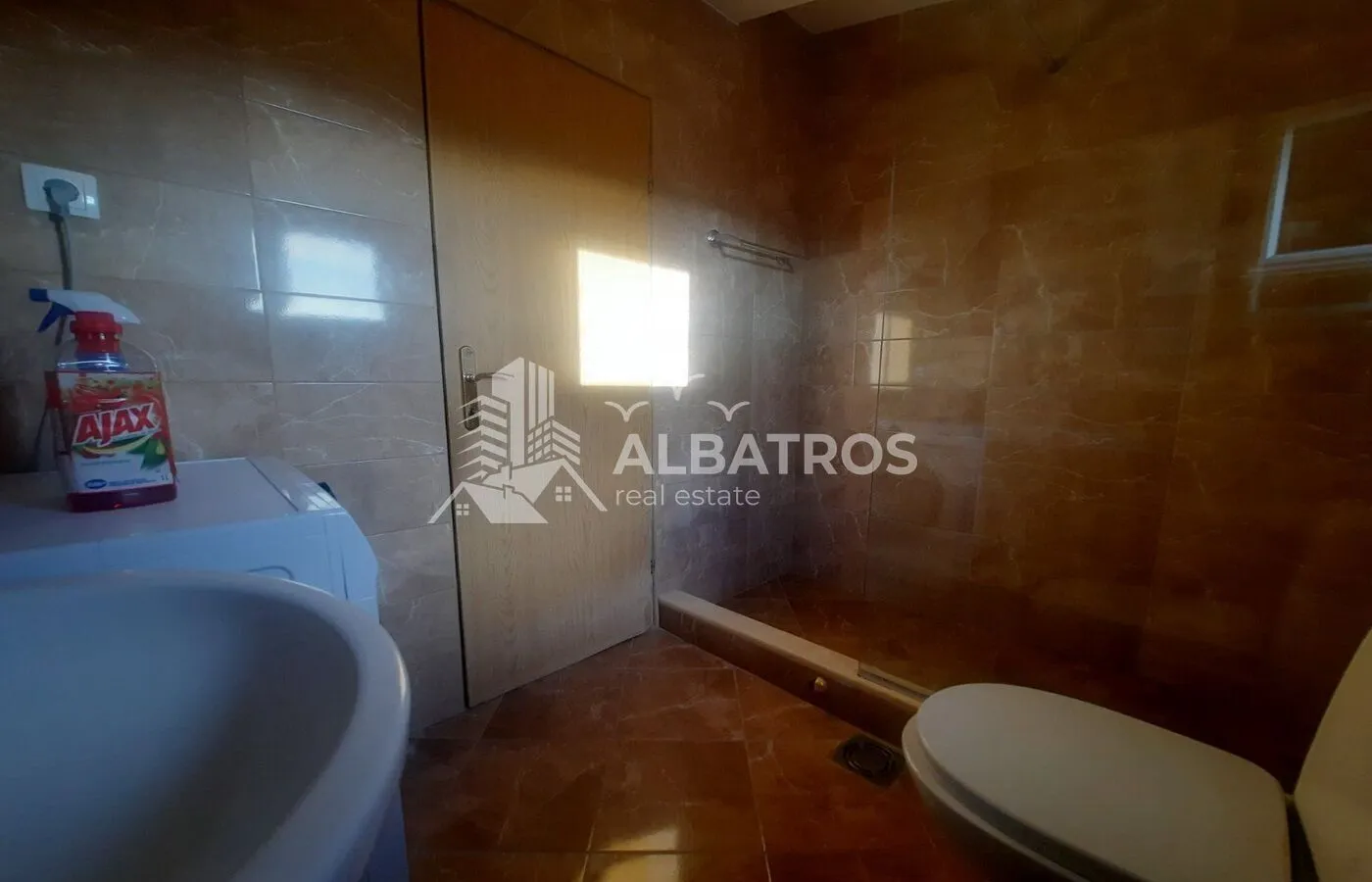 Bathroom lined with ceramic tiles and a walk-in shower.