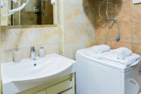 Kupatilo sa umivaonikom, ogledalom i veš mašinom na kojoj su složeni peškiri. - image 13