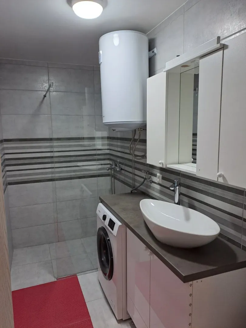 Modern bathroom with a glass shower cabin, washing machine, and boiler.