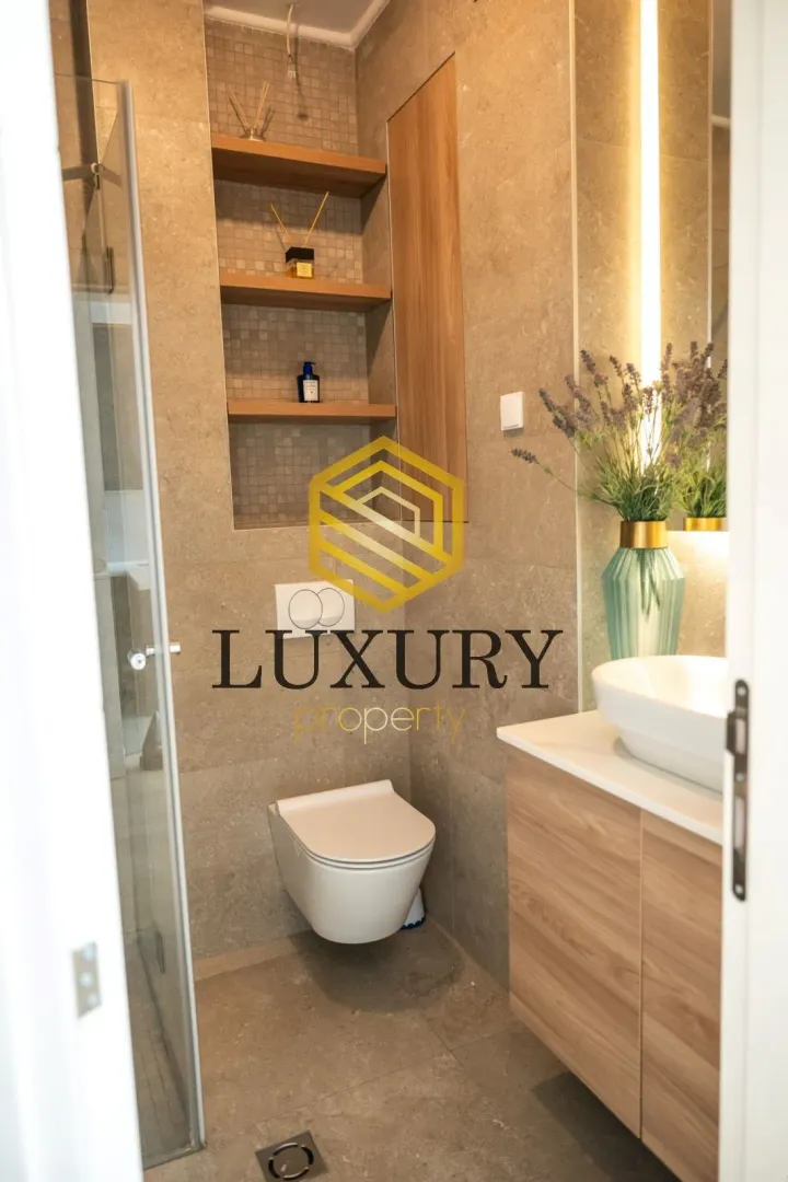 A modern bathroom equipped with a walk-in shower, toilet, and vanity sink.