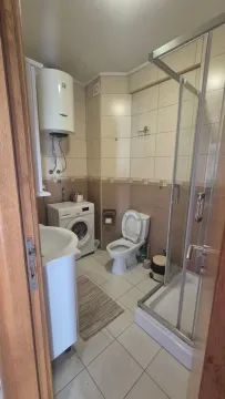 View of the bathroom with a shower cabin, sink, washing machine, and toilet. - image 9
