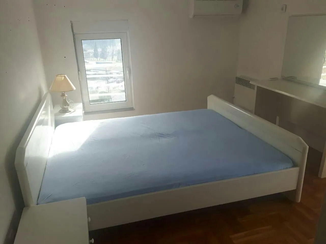 Jednostavna spavaća soba sa bračnim krevetom i prozorom.