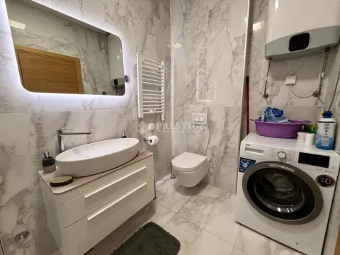 Modernly equipped bathroom with a washbasin, toilet, and washing machine. - image 13