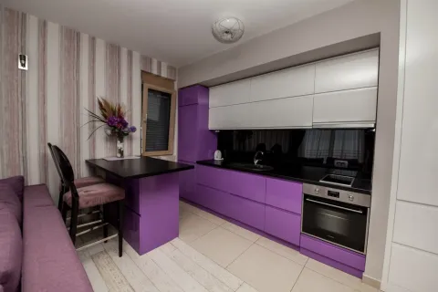 Moderna kuhinja sa ljubičastim i bijelim elementima i šankom. - image 4