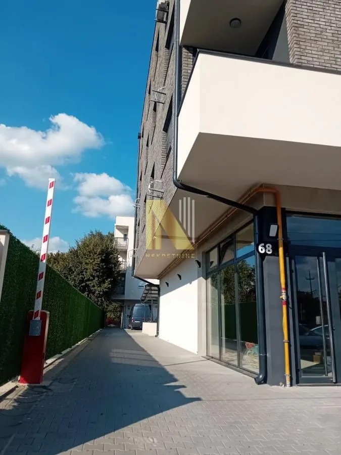 Pogled na spoljašnjost zgrade sa popločanim prolazom i ulazom.