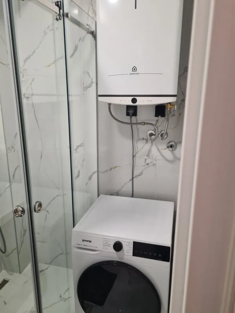 Part of a bathroom with a washing machine and water heater.