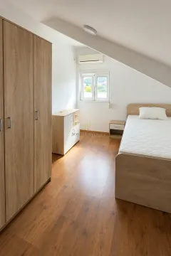 Attic bedroom with a wooden bed, wardrobe, and laminate flooring. - image 8