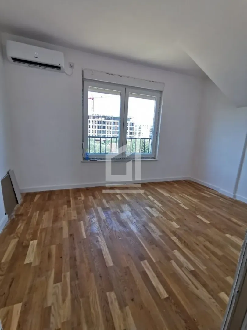 Empty room with parquet flooring and an air conditioning unit on the wall.