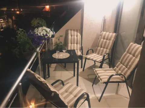 Namješten balkon sa stolom, stolicama i cvijećem u večernjoj atmosferi. - image 3