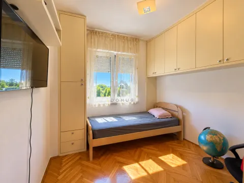 Manja spavaća soba sa krevetom, ugradnim ormarima i televizorom na zidu. - image 12