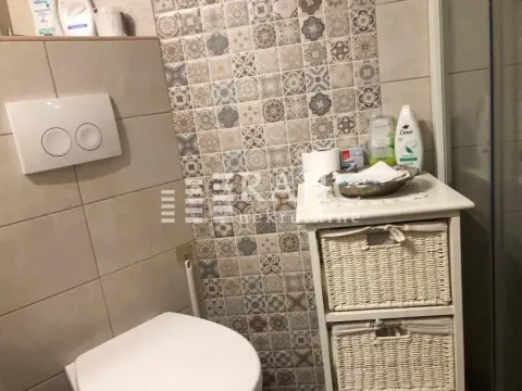View of the bathroom with a toilet and a chest of drawers with wicker baskets. - image 11