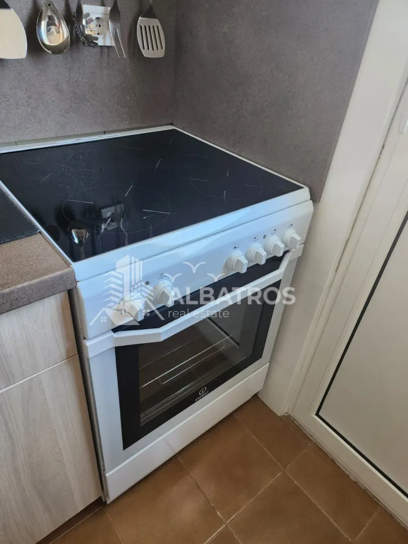 Bijeli električni šporet sa staklokeramičkom pločom u kuhinji.