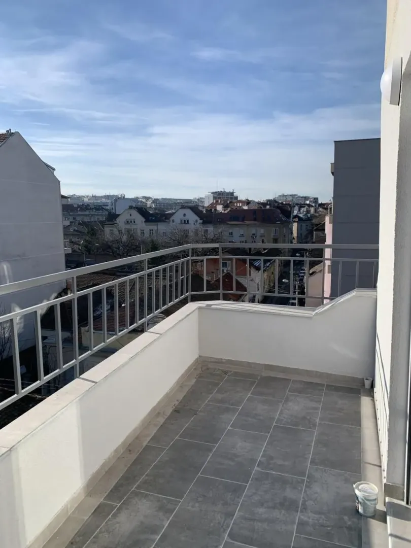 Balcony with tiled flooring, metal railing, and city view.