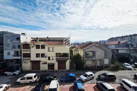 View from the apartment overlooking surrounding buildings and a parking lot with vehicles. - image 15