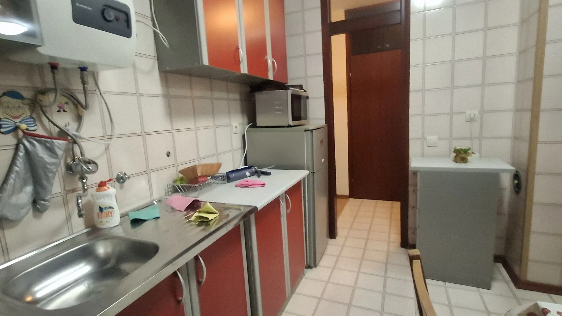 Manja kuhinja sa crvenim elementima i sudoperom.