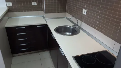 Manja kuhinja sa tamnim elementima, bijelom radnom površinom i sudoperom. - image 7