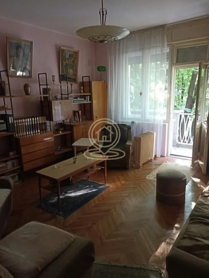 Dnevna soba sa drvenim nameštajem i izlazom na terasu.