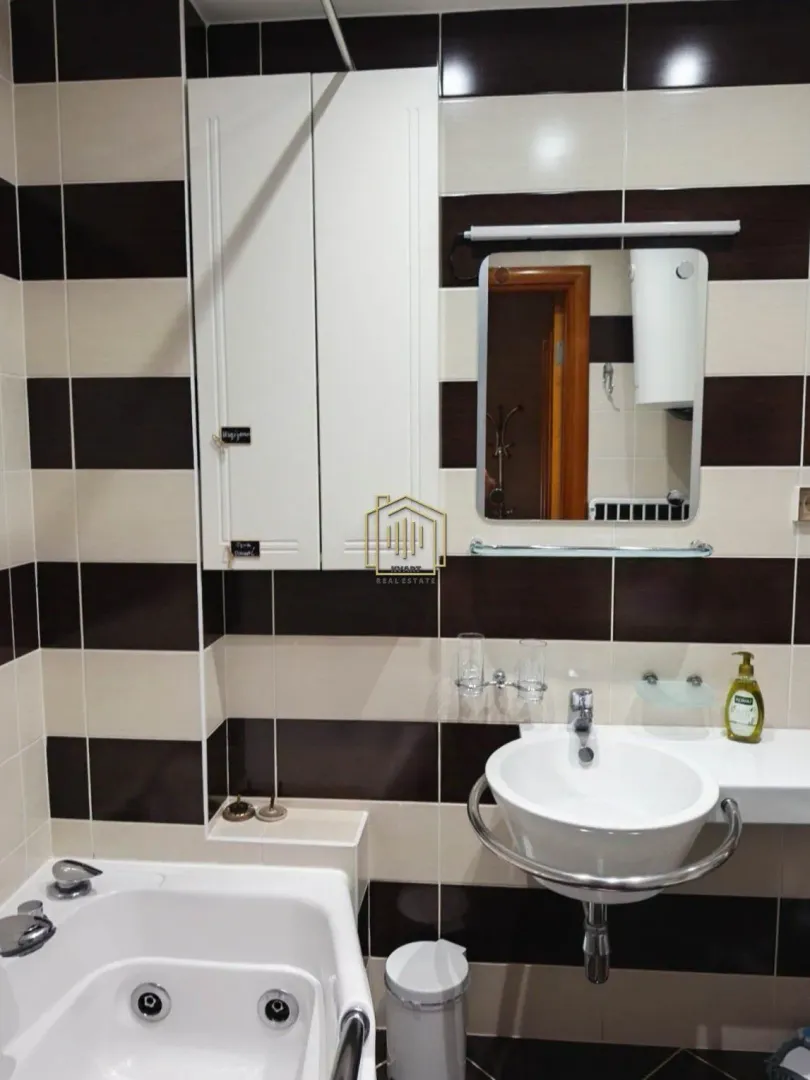 Bathroom equipped with a washbasin, mirror, bathtub, and wall cabinet.