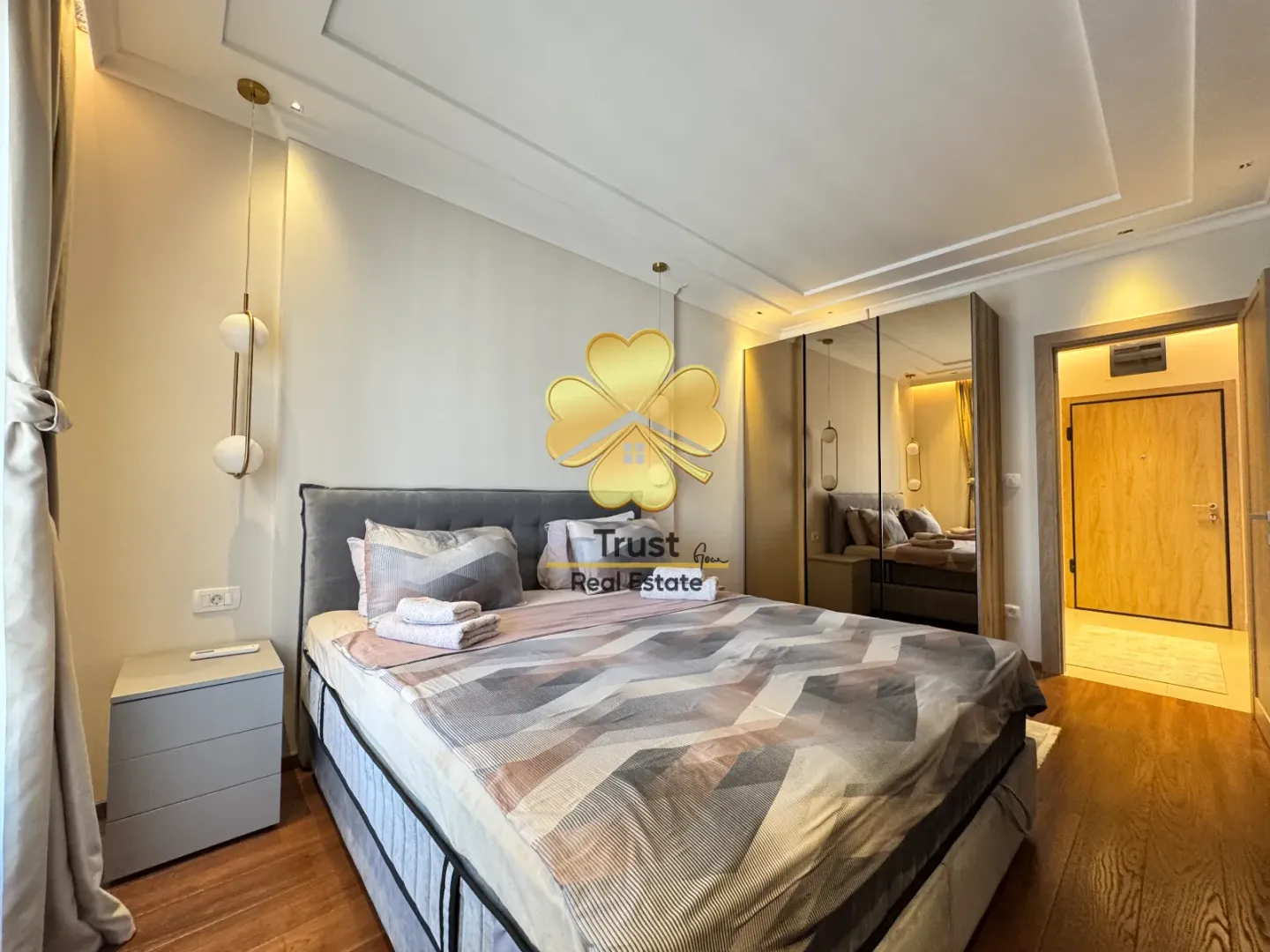 Modern bedroom with a double bed, mirrored wardrobe, and lighting.