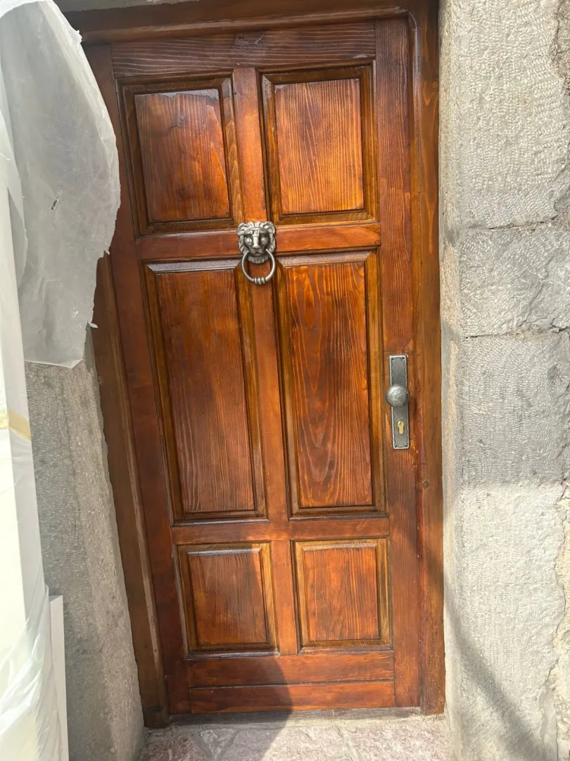 Drvena ulazna vrata sa ukrasnim metalnim detaljem.