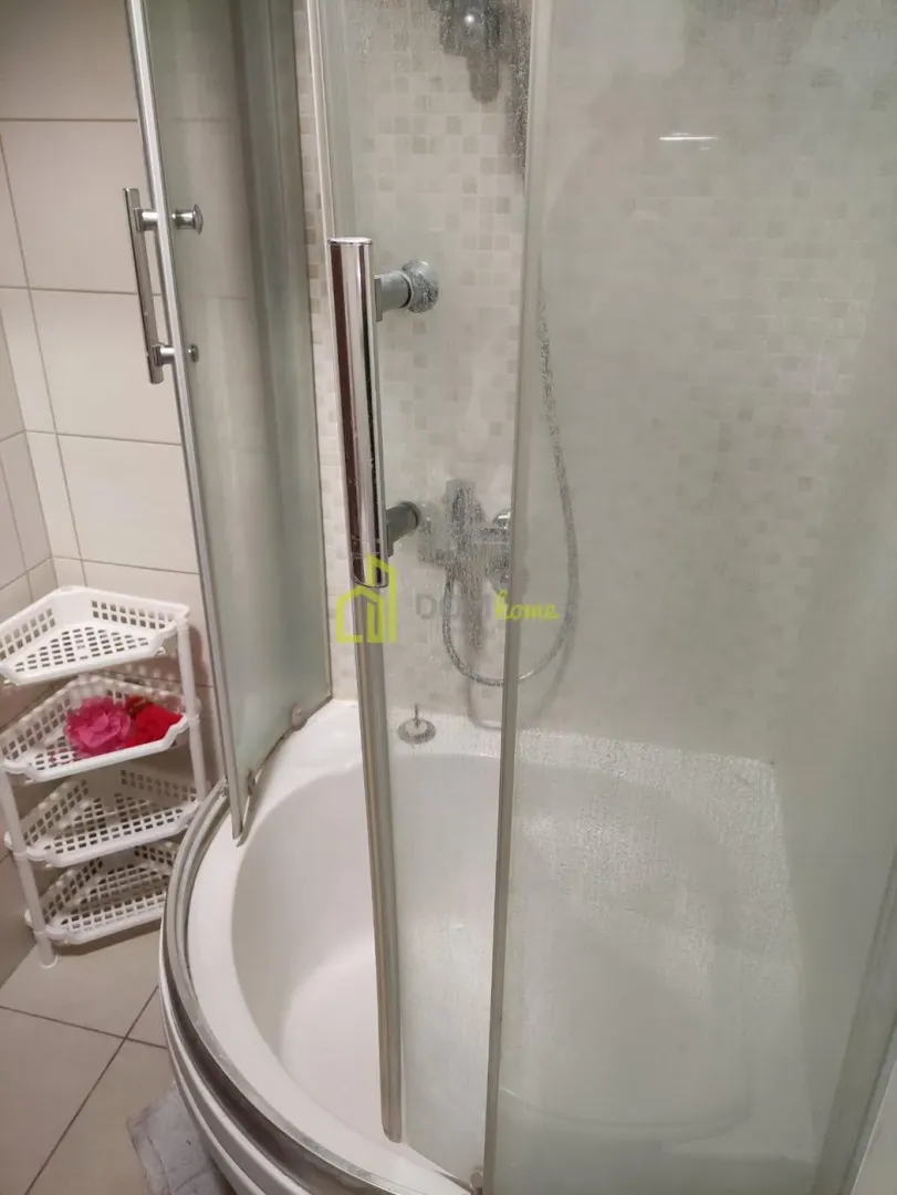 Kupatilo sa tuš kabinom i bijelim pločicama.