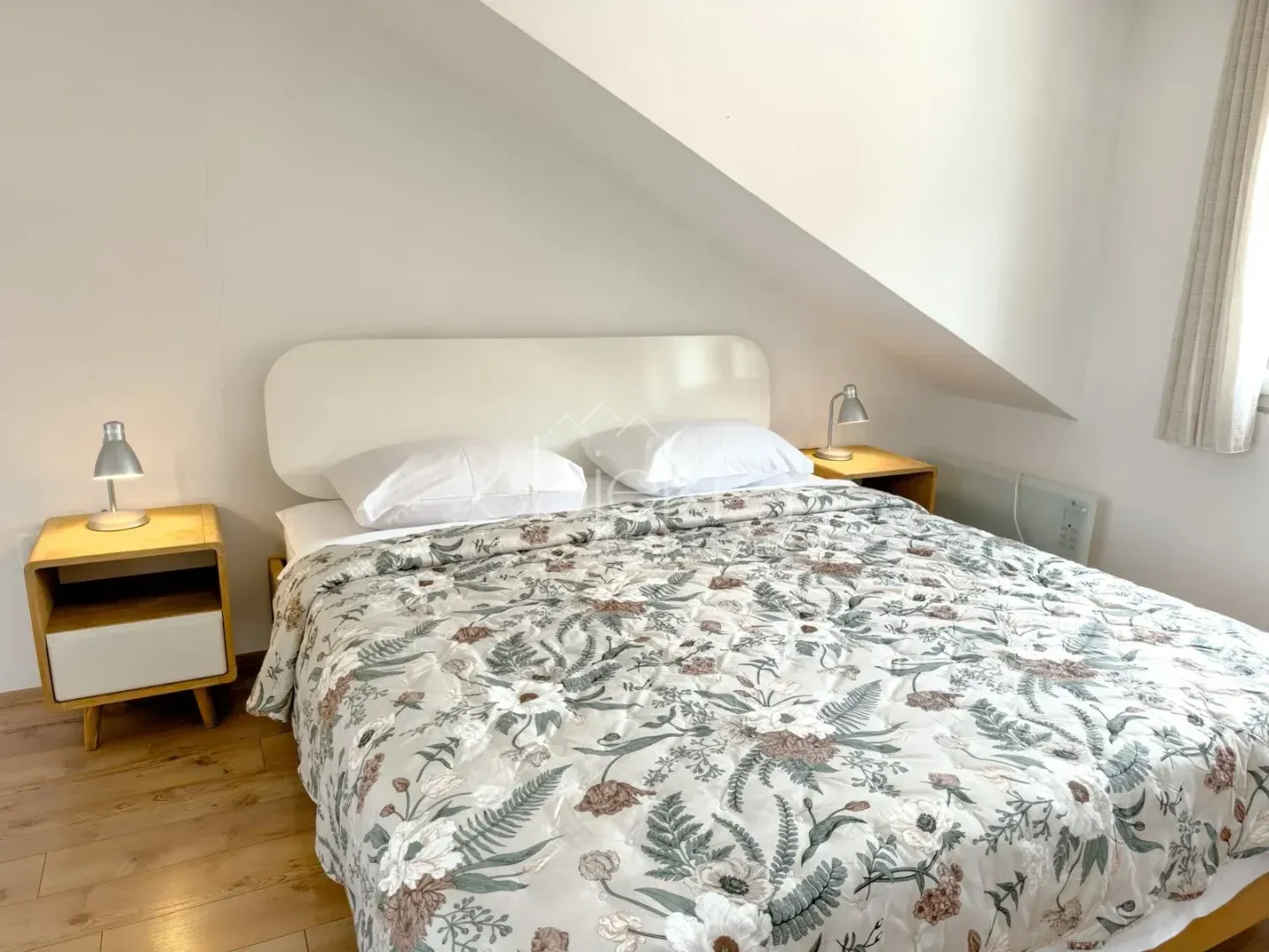 Bedroom with a double bed, bedside tables and lamps.