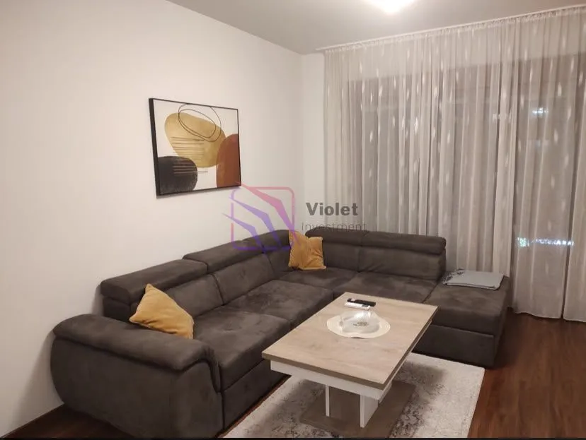 Living room with a sectional sofa, coffee table, and decorative wall art.