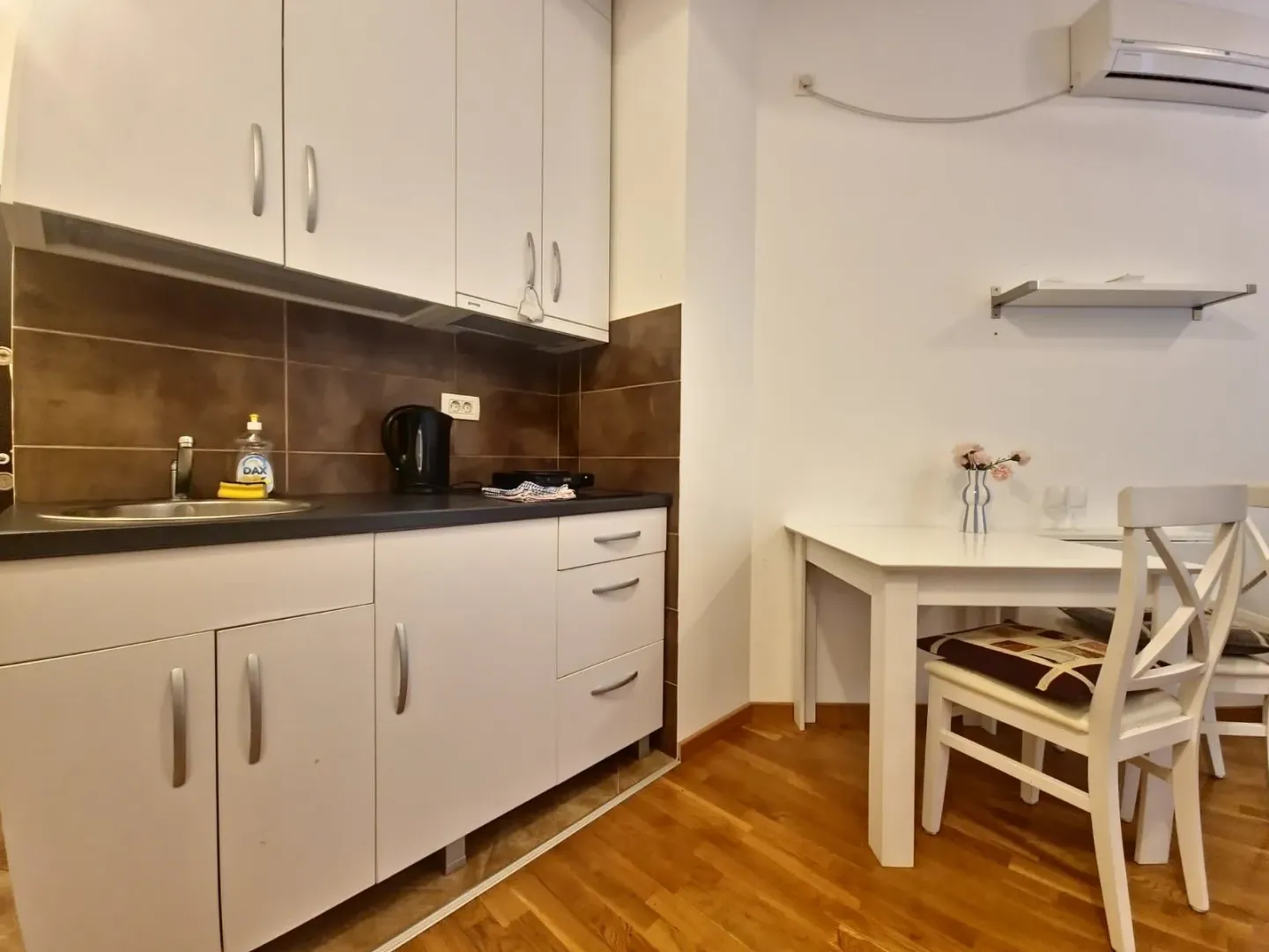 Compact kitchen with white cabinets and a dining table.