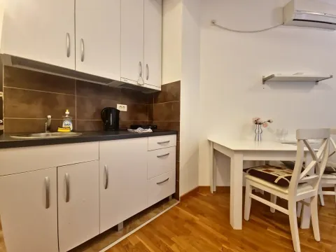 Compact kitchen with white cabinets and a dining table. - image 7