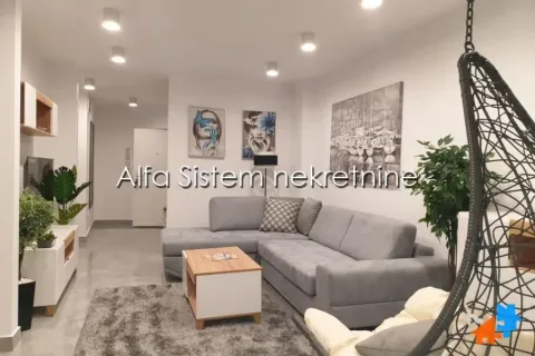 Dnevna soba sa sivom ugaonom garniturom, stočićem i dekorativnim slikama na zidu. - image 11