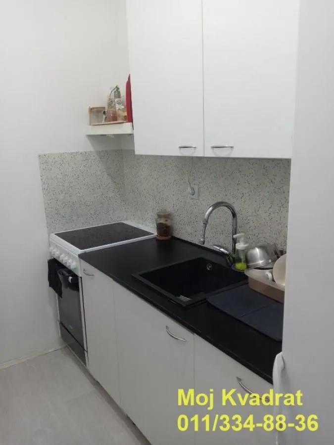Small white kitchen with a dark countertop and a stove.