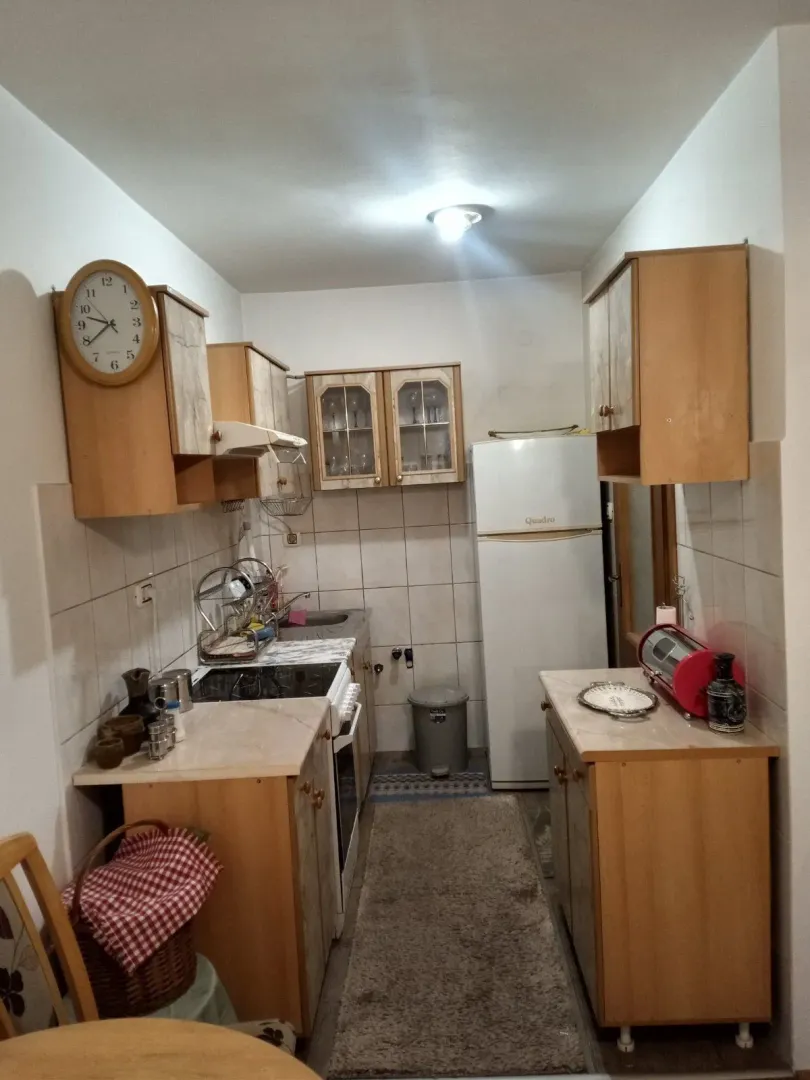 Kuhinja sa drvenim elementima, bijelim frižiderom i šporetom.