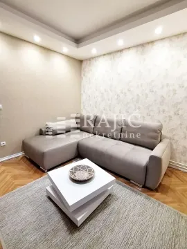 Living room with a sectional sofa, coffee table, and recessed ceiling lighting. - image 2