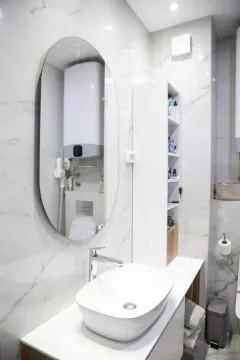 Savremeno opremljeno kupatilo sa umivaonikom, ogledalom i bijelim pločicama. - image 4