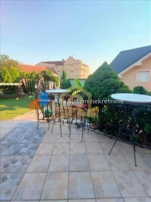 Spacious terrace with tables and chairs, overlooking the yard.