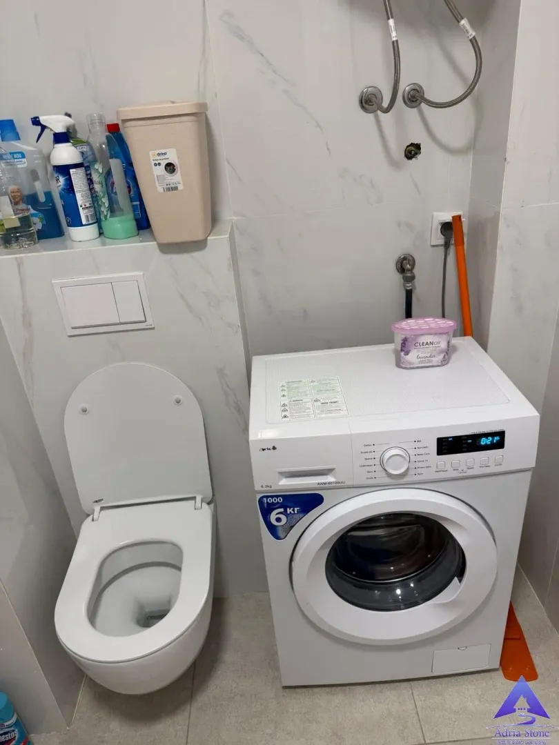 Kupatilo opremljeno toaletom i veš mašinom.