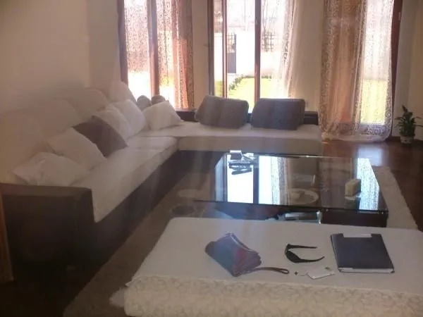 A bright living room featuring a large corner sofa and a glass coffee table.