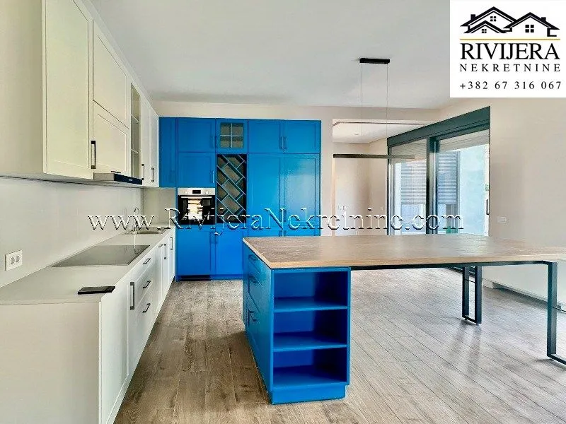 Modern kitchen with white and blue cabinets and a large dining table.