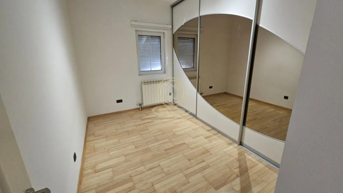 Empty bedroom with a built-in wardrobe and hardwood flooring.