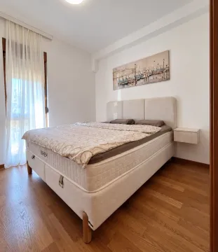 Svijetla spavaća soba sa bračnim krevetom, drvenim podom i balkonskim vratima. - image 7