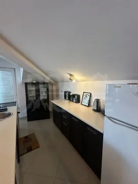 Pogled na kuhinju sa tamnim elementima i bijelim frižiderom u potkrovlju. - image 6