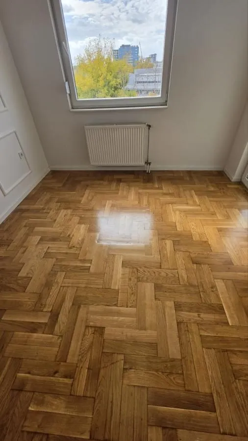 Prazna prostorija sa parketom i prozorom.
