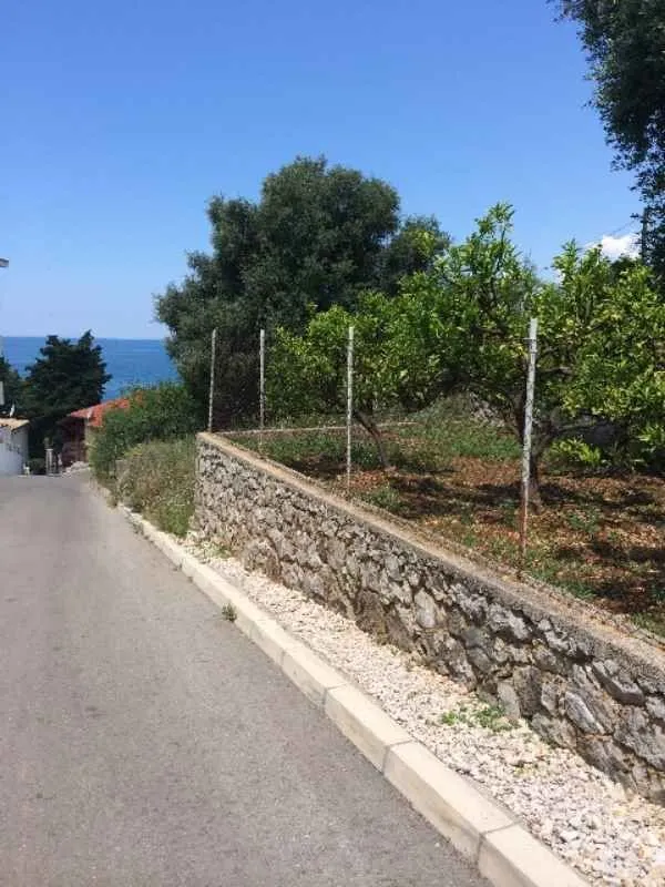 Pogled na put i dvorište oivičeno kamenim zidom.