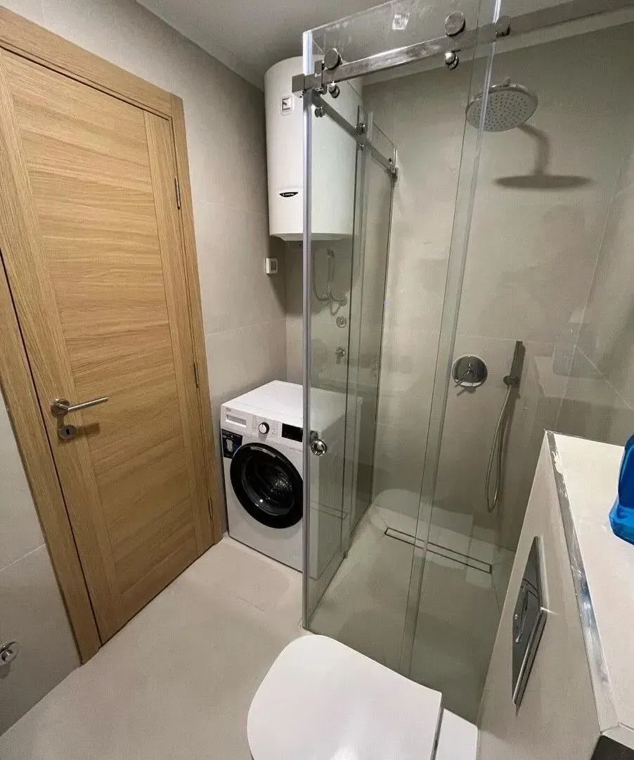 Modern equipped bathroom with a walk-in shower and washing machine.