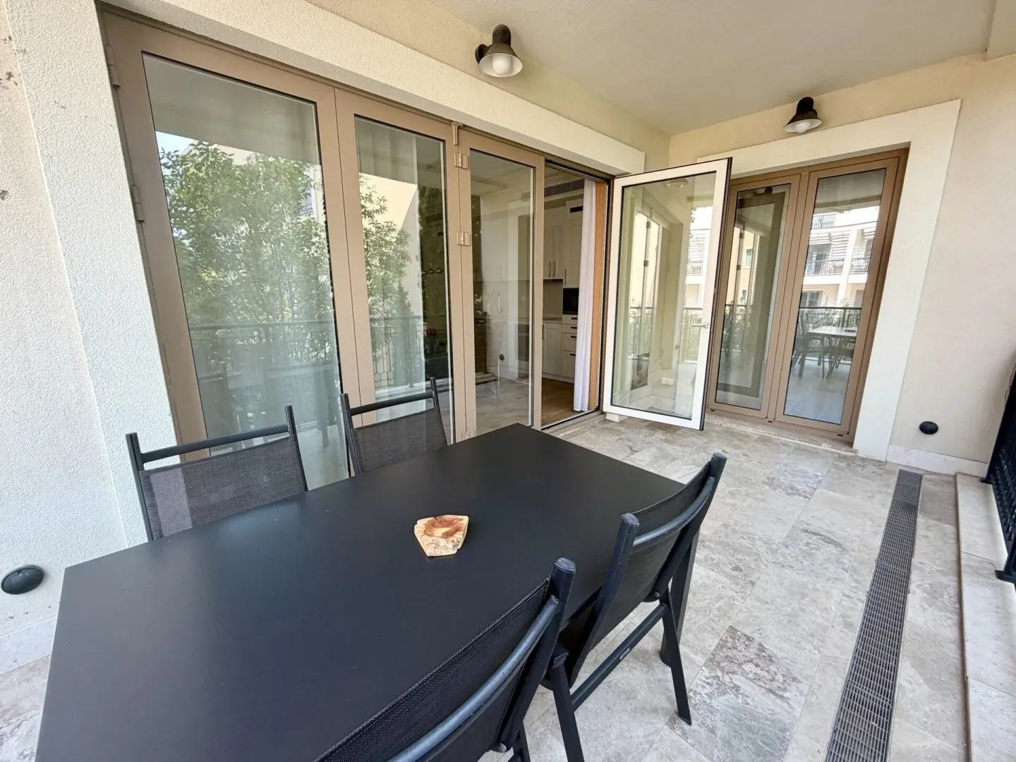 Natkrivena terasa sa trpezarijskim stolom i stolicama, i pogledom na unutrašnjost apartmana.