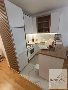 Moderna kuhinja sa belim elementima, ugradnim aparatima i šankom. - image 7
