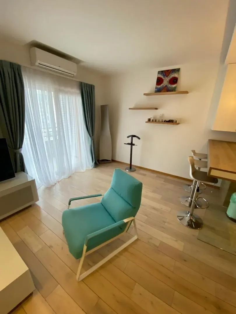 Svijetla dnevna soba sa tirkiznom foteljom i šankom.